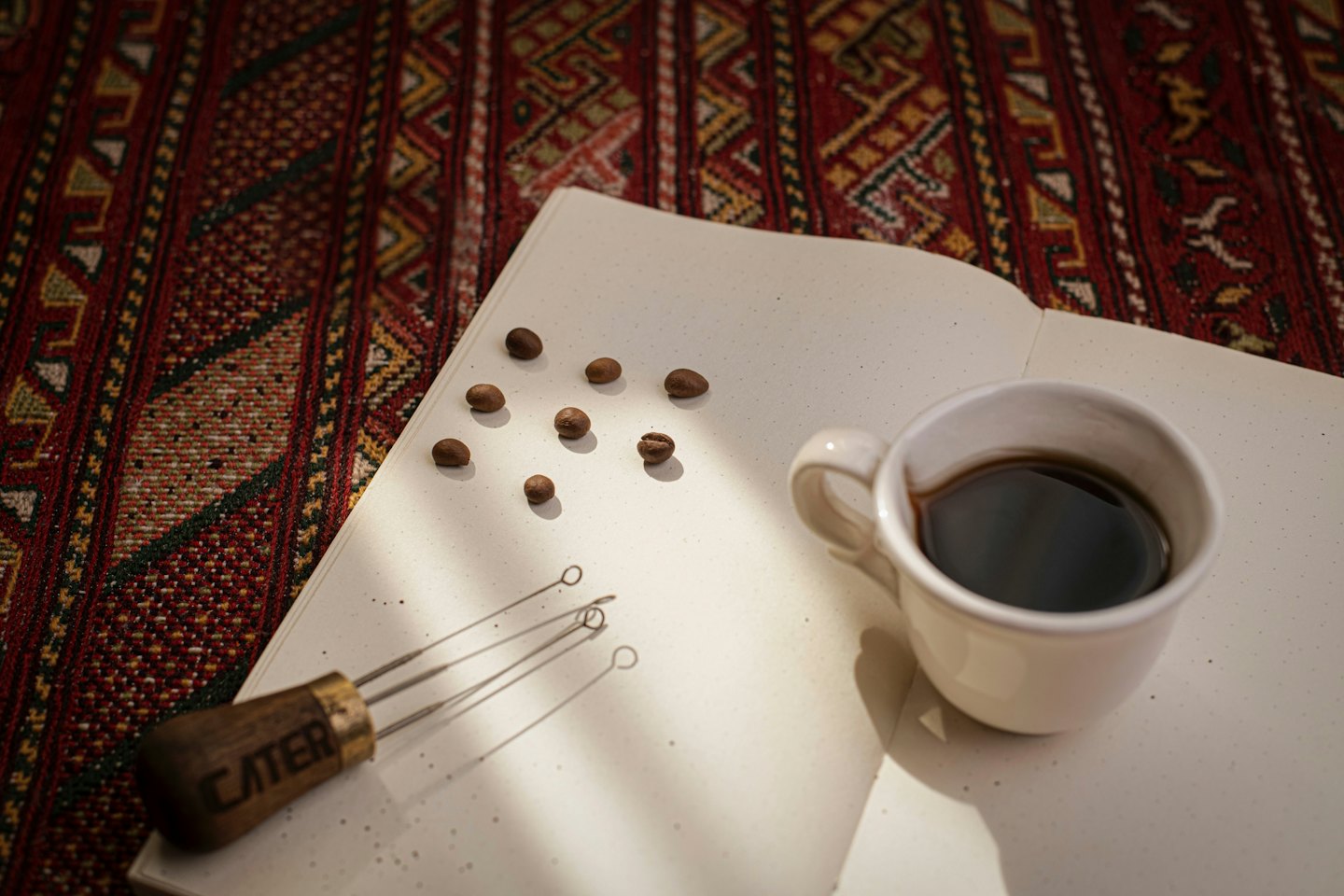 Roasted coffee beans and a ceramic cup rest on a notebook.